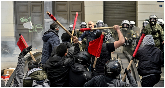 Protesters clash with riot police at the entrance of a metro station during a demonstration in Athens on March 5, 2023, following a deadly train accident late on February 28. Violent clashes broke out between police and protesters outside the Greek parliament in Athens on March 5 as thousands attended a rally following the nation's worst rail disaster that killed 57, AFP reporters saw. (Photo by Louisa GOULIAMAKI / AFP)