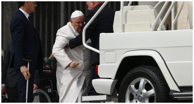 Pope Francis is helped get up the popemobile car as he leaves on March 29, 2023 at the end of the weekly general audience at St. Peter's square in The Vatican. Pope Francis has been at the Gemelli Hospital in Rome since the afternoon of March 29, 2023 for some previously scheduled check-ups, the Holy See press director said. (Photo by Vincenzo PINTO / AFP)