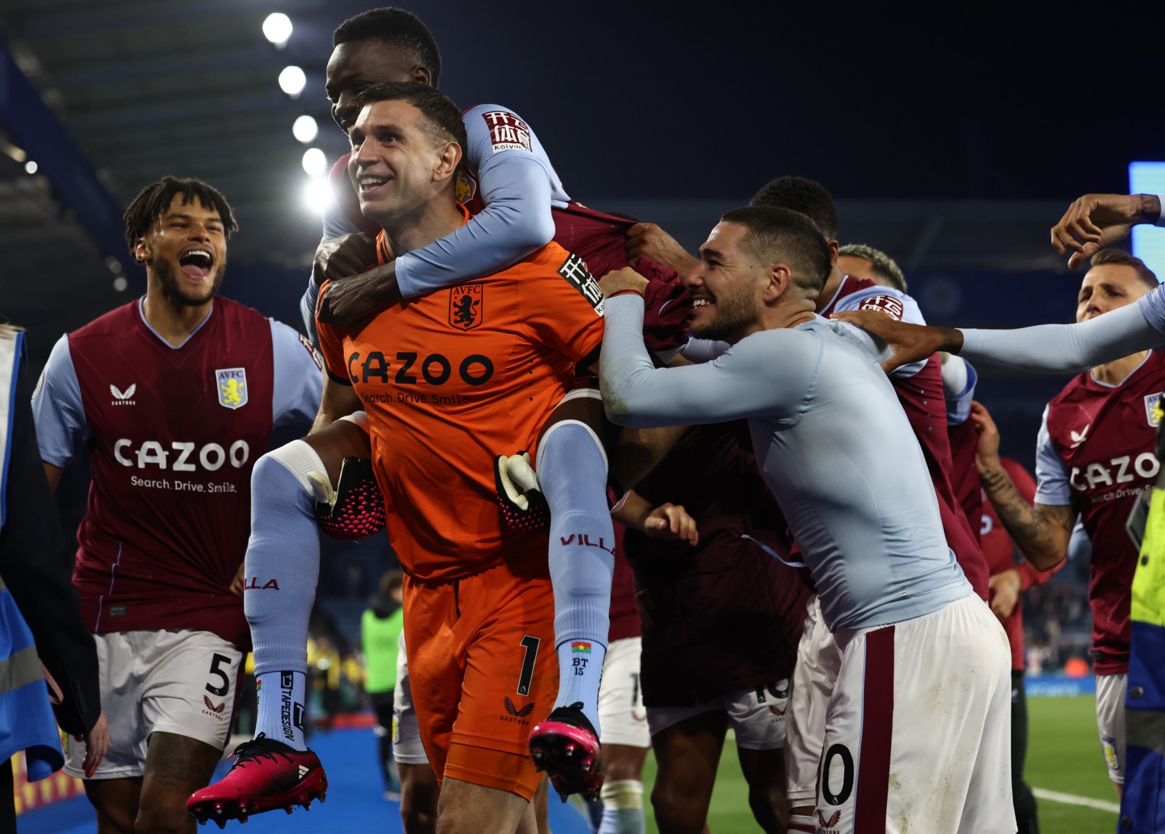 Aston Villa's Burkinese midfielder Bertrand Traore (2L) jumps on the back of Aston Villa's Argentinian goalkeeper Emiliano Martinez (C) as Aston Villa's players celebrate on the pitch after the English Premier League football match between Leicester City and Aston Villa at King Power Stadium in Leicester, central England on April 4, 2023. (Photo by DARREN STAPLES / AFP) /