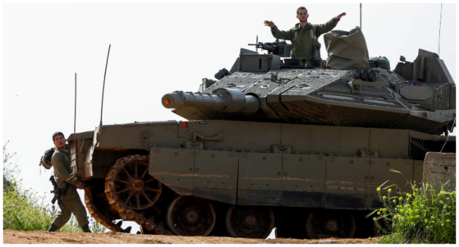 Israeli soldiers take up a position with a tank near Shtula, bordering Lebanon, on April 7, 2023. Israel launched air strikes before dawn on April 7 in the Gaza Strip and Lebanon, saying it was targeting Palestinian militant group Hamas in retaliation for several dozen rockets fired at Israel from both territories. (Photo by Jalaa MAREY / AFP)