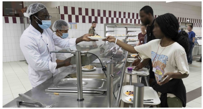 This handout photograph taken on April 23, 2023 and released by the Etat Major des Armees (French defence staff) shows people having dinner after their arrival at the Airbase 188 in Djibouti on April 23, during the "Sagittaire" evacuation of around 100 people from Sudan on the first French flight out of the war-hit country after a "complicated" rescue operation. (Photo by ADJ Laure-Anne MAUCORPS ep DERRI / Etat Major des Armées / AFP)