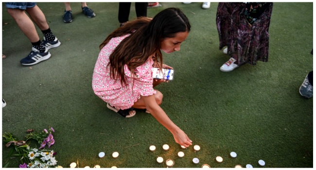 A youth lights candles at a playground in the "Jardins de l'Europe" in Annecy, in the French Alps, on June 8, 2023, following a mass stabbing in the park of the city. (Photo by OLIVIER CHASSIGNOLE / AFP)