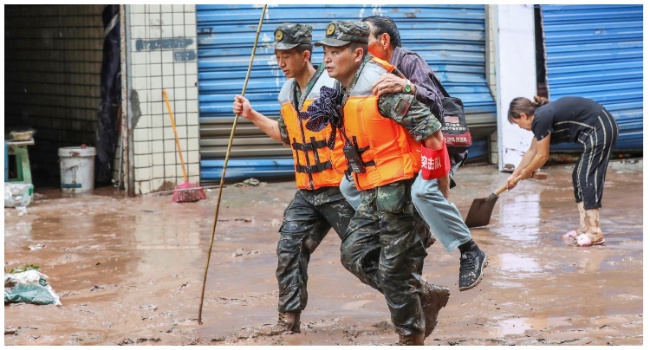 This file photo taken on July 4, 2023 shows paramilitary policemen evacuating a resident after flooding caused by heavy rains in China's southwestern Chongqing. (Photo by AFP)