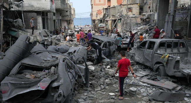 Palestinians carrying personal belongings walk past heavily damaged buildings following Israeli airstrikes on Gaza City's al-Rimal district, on October 10, 2023. Israel kept up its deadly bombardment of Hamas-controlled Gaza on October 10 after the Palestinian militant group threatened to execute some of the around 150 hostages it abducted in a weekend assault if air strikes continue without warning. (Photo by Mahmud HAMS / AFP)