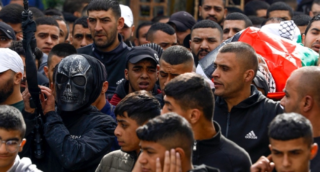 A masked armed fighter attends the funeral of a Palestinian man who was killed in an Israeli raid in the Balata refugee camp.