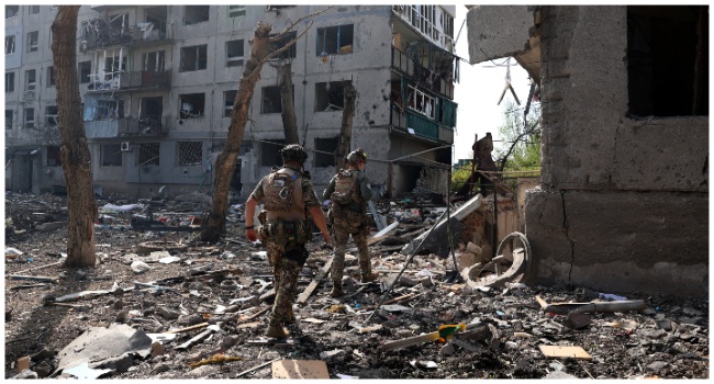 Officers of the special police force "White Angel" Hennadiy Yudin 47(L) and Dmytro Solovyi 23 (R) walk past destroyed buildings and debris during the evacuation of local residents from the village of Ocheretyne not far from Avdiivka town in the Donetsk region, on April 15, 2024, amid the Russian invasion in Ukraine. (Photo by Anatolii STEPANOV / AFP)