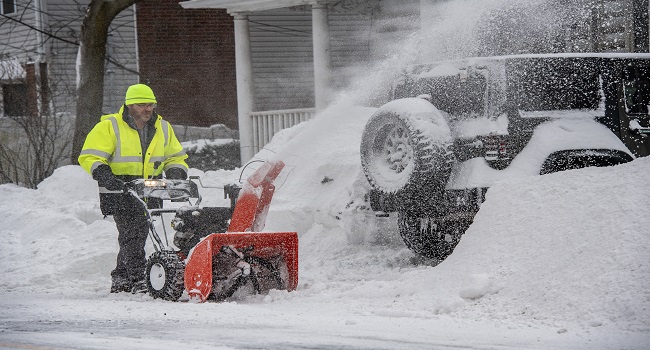 A person uses as snowblower to remove snow from their driveway in Winthrop, Massachusetts on January 26, 2026. A monster storm barreling across the United States had killed at least 11 people on Monday, prompting warnings to stay off the roads, mass flight cancelations and power outages after a weekend of misery. (Photo by Joseph Prezioso / AFP)