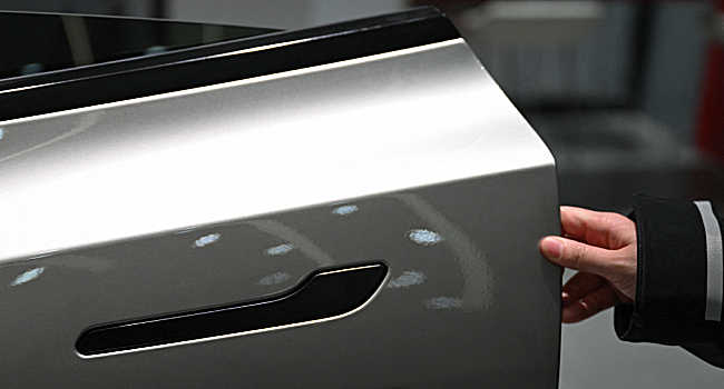 A woman opens the door for a Tesla Model YL electric vehicle