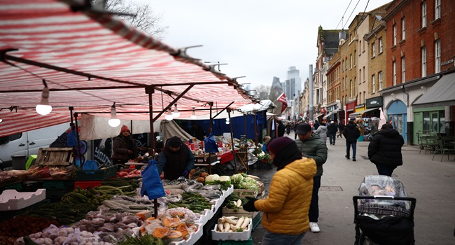 People look at fruit and vegetables displayed for sale on a market stall on Whitechapel High Street in east London on February 12, 2026. (Photo by HENRY NICHOLLS / AFP)