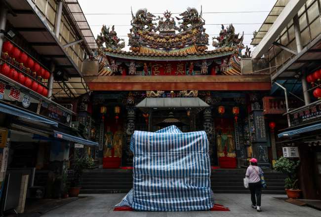TOPSHOT - Statues outside Keelung's Dianji Temple are covered with protective tarpaulins ahead of the arrival of Typhoon Bavi in Keelung on July 10, 2026 (Photo by I-Hwa Cheng / AFP)